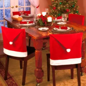 Detail of red Christmas hat chair covers with white plush pompoms in a festive dining room