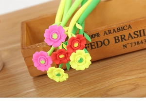 Close-up of colorful camellia flower shaped pens in a wooden holder on a desk