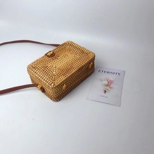 Detail of rectangular rattan crossbody bag with brown leather strap and buckle closure