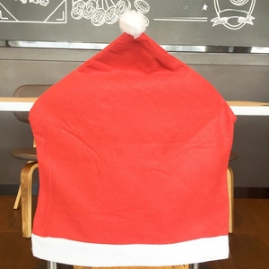 Detailed view of red and white Santa hat chair covers on wooden dining chairs
