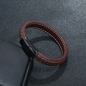 Macro shot of brown braided leather bracelet with black magnetic clasp and white stitching