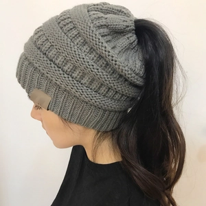 Detail view of medium grey cable knit ponytail beanie with a brown leather patch