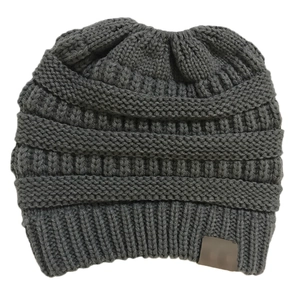 Detailed view of dark grey chunky knit beanie featuring a decorative leather patch detail
