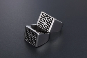 Detail of square vintage steel rings featuring cross motifs and textured polka dot patterns
