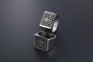Detailed view of two vintage men's signet rings with cross pattern and dotted texture