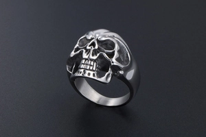 Macro shot of silver titanium steel skull ring with high-gloss finish on black background