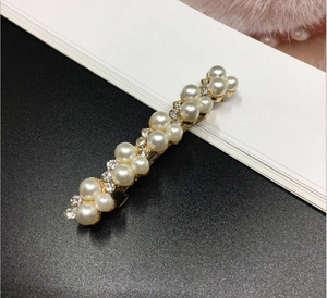 Close-up of golden hair clip with elegant white pearls and sparkling clear rhinestones
