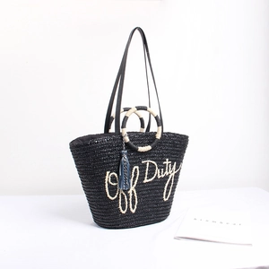 Black handmade straw woven tote bag with Off Duty text and tassel for beach travel