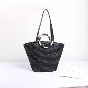 Handwoven straw tote bag with dual ring handles and leather straps for beach vacation