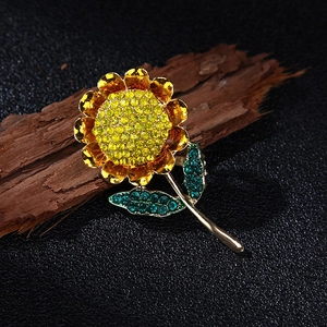 Detailed view of sunflower brooch with yellow and green crystals on dark wood surface