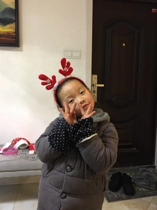 Detail of a child wearing red reindeer antler headband with white snowflake patterns