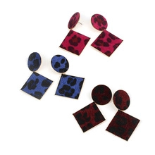 Gros plan de boucles d'oreilles léopard carrées en magenta, bleu roi et marron