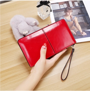Close-up of a red glossy long wallet with zipper closure and a convenient wrist strap