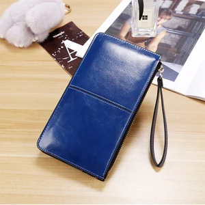 Detail of blue long wax leather wallet with wrist strap on an elegant wooden tabletop