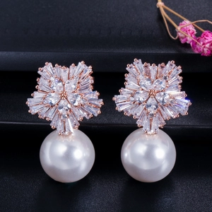 Macro shot of rose gold flower earrings with zircon pavé and white shell pearls