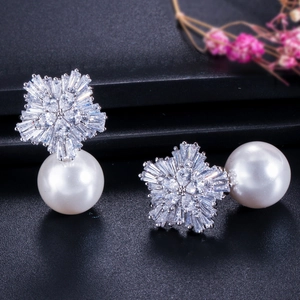 Detail shot of micro-paved zircon snowflake earrings with elegant white round pearls