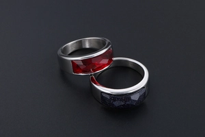Macro detail of stainless steel rings with faceted red zircon and blue sandstone gems