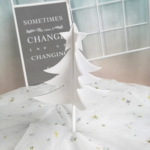 3D white acrylic Christmas tree cake topper decoration on a gold star tulle backdrop