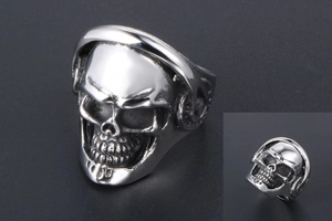 Macro detail of silver punk skull ring featuring integrated headphone design on dark background