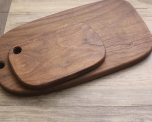 Top view of two solid walnut wood cutting boards with natural grain and handles