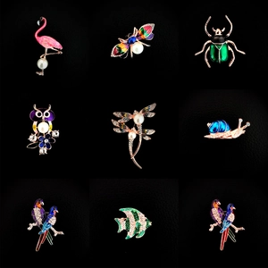 Set aus neun bunten Emaille-Tierbroschen mit Flamingos und Eulen auf schwarzem Hintergrund