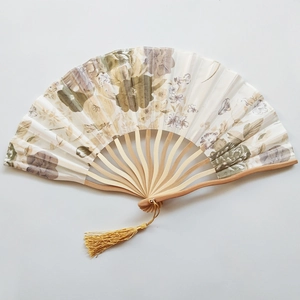 Japanese style bamboo folding fan with floral print and elegant gold tassel on white background