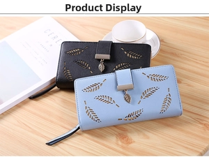 Detail view of long wallets featuring hollow leaf patterns and metal charms on a desk