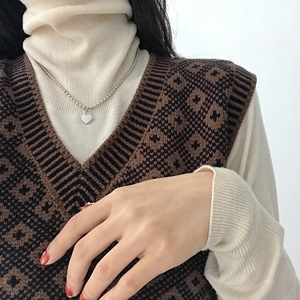 Detailed view of S925 sterling silver heart necklace worn over a white turtleneck sweater
