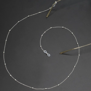 Detailed view of silver metal eyewear chain with small beads and rubber loop connectors