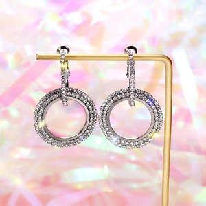 Detail view of silver leverback earrings with pavé crystals on a jewelry stand