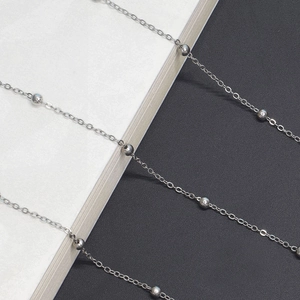 Macro shot of minimalist silver metal eyewear chain with polished beads on a bicolor backdrop