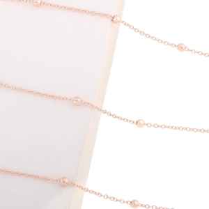 Macro shot of minimalist rose gold metal bead chain with polished finish and fine links