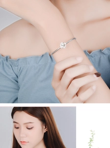 Dettaglio del bracciale loto in argento con perla bianca e design floreale sul polso
