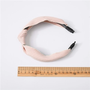 Detail view of pink plaid knot headband next to a ruler showing its 15cm width