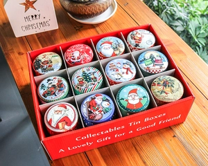 Detail of 12 mini Christmas tin boxes in a red gift box set on a rustic wooden table
