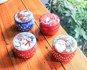 Detailed view of colorful Christmas tin containers on a warm wooden tabletop with greenery