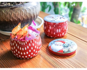 Close-up of a red tinplate Christmas jar with Santa and Reindeer on a wooden table