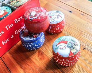 Detail of Christmas tin boxes with festive Santa and elk prints on a wooden surface