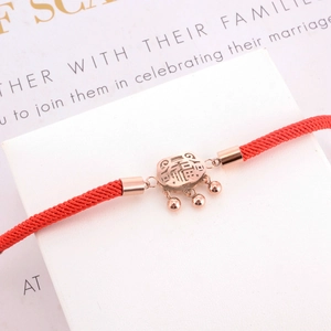 Red cord bracelet with rose gold luck lock charm featuring the Fu character on a gift card