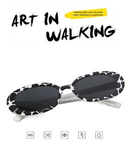 Detailed close-up of retro oval sunglasses featuring a trendy black and white cow print frame
