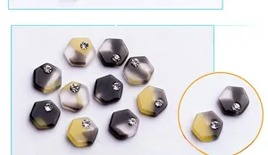 Macro detail of hexagonal nail art charms with marble gradient pattern and crystal rhinestones