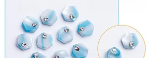 Macro view of hexagonal marble pattern nail art charms with blue gradient and rhinestones