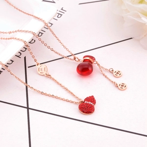 Collana in oro rosa con pendenti a forma di zucca rossa e strass su sfondo floreale bianco