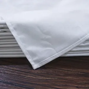 Stack of thick white cotton napkins with fine overlock edges on a dark wooden table