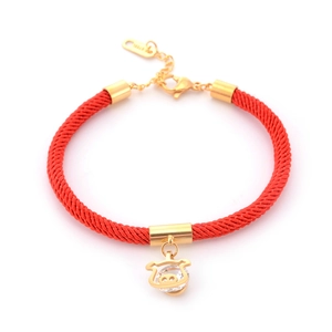 Detail of red braided rope bracelet with gold pig charm and sparkling crystal inlay