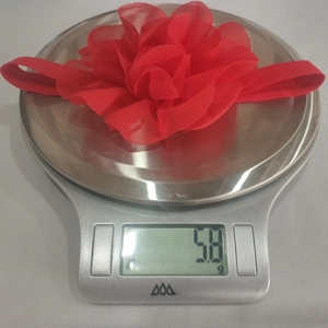 Detailed view of red chiffon flower baby headband weighing 5.8g on a digital scale