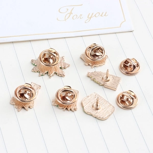 Reverse side of 6 rose gold enamel pins with butterfly clasps on minimalist paper