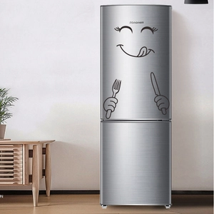 Detail showing cartoon kitchen fridge stickers with smiling face and cutlery on silver surface