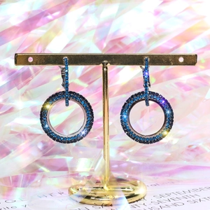 Detail of geometric silver hoop earrings with dark blue and black zircon on gold stand