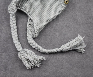 Close-up of cable knit texture and braided tassels on children's winter trapper hat